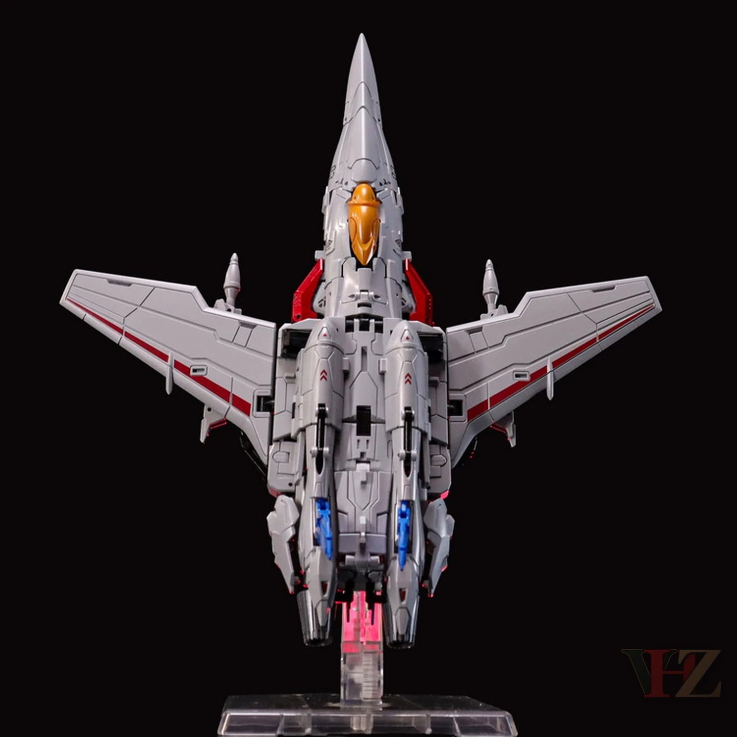 Rear view of Collection Space CS-03 Starqueen Starscream jet mode figure, gray with red accents, orange nose, blue details, on clear stand.