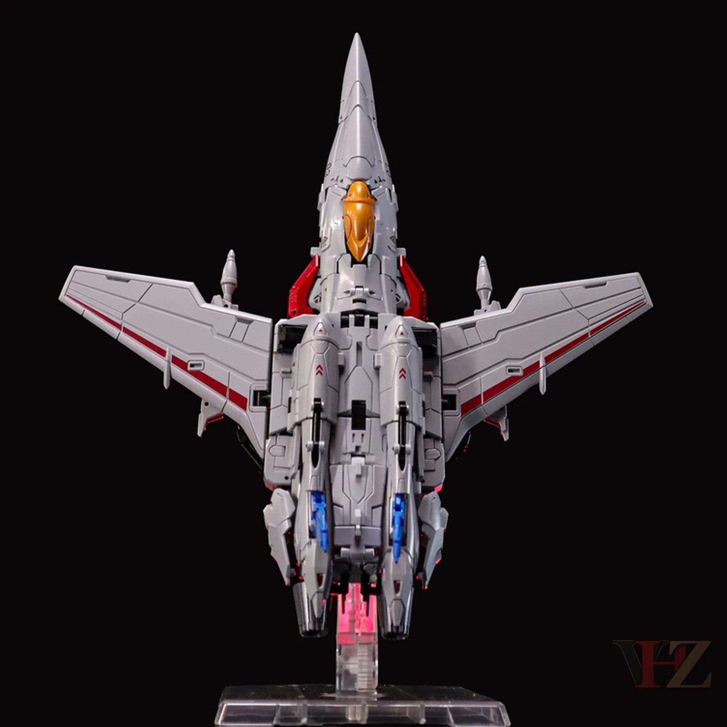 Rear view of Collection Space CS-03 Starqueen Starscream jet mode figure, gray with red accents, orange nose, blue details, on clear stand.