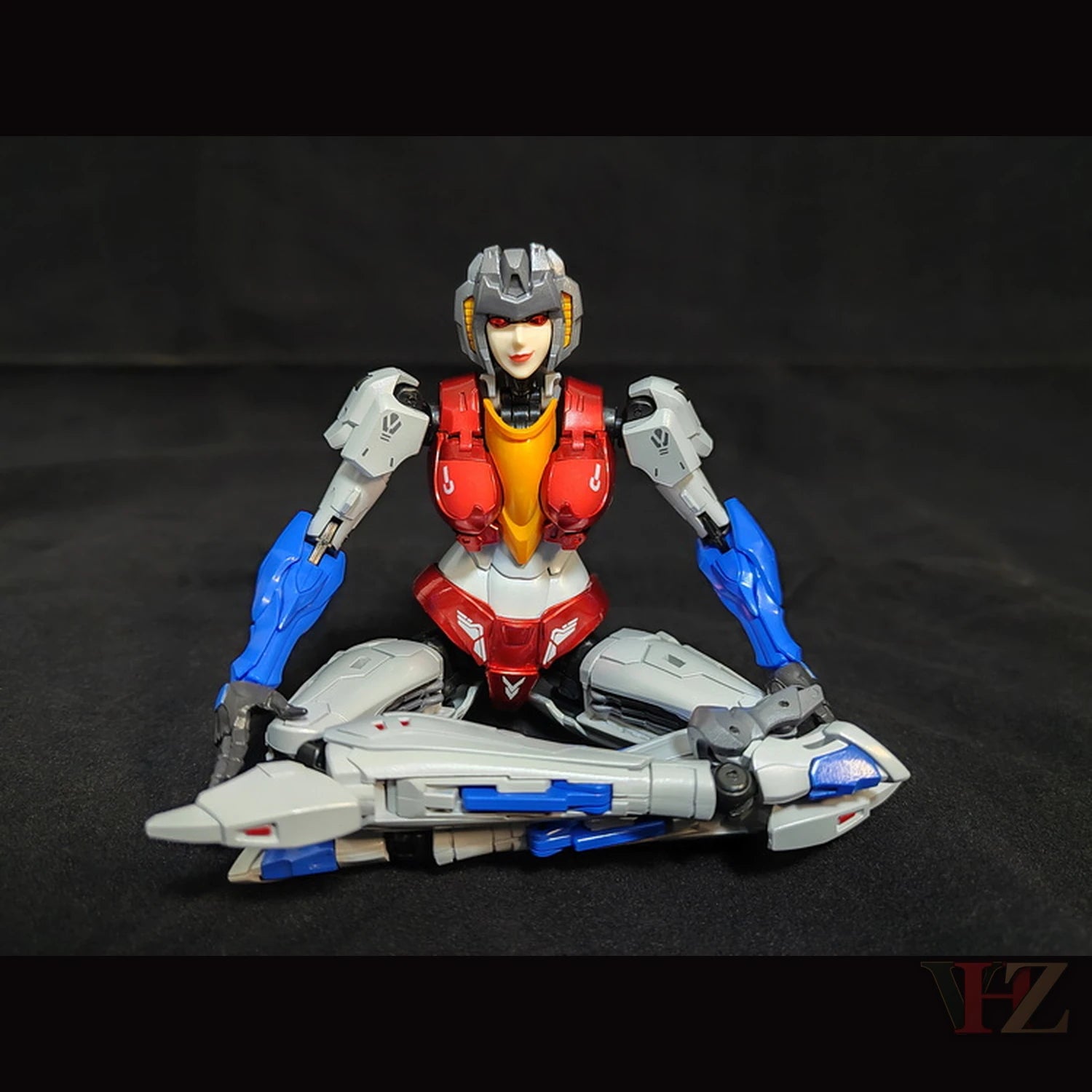 Collection Space CS-03 Starqueen Starscream Mecha Girl sitting cross-legged with jet mode, white/red/blue body, against black.