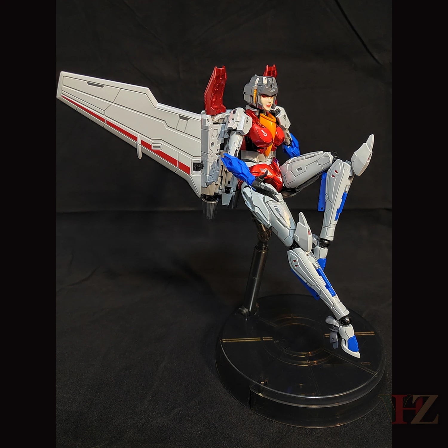 Collection Space CS-03 Starqueen Starscream Mecha Girl seated with one leg raised, white/red/blue body, large wing, on clear stand against black.