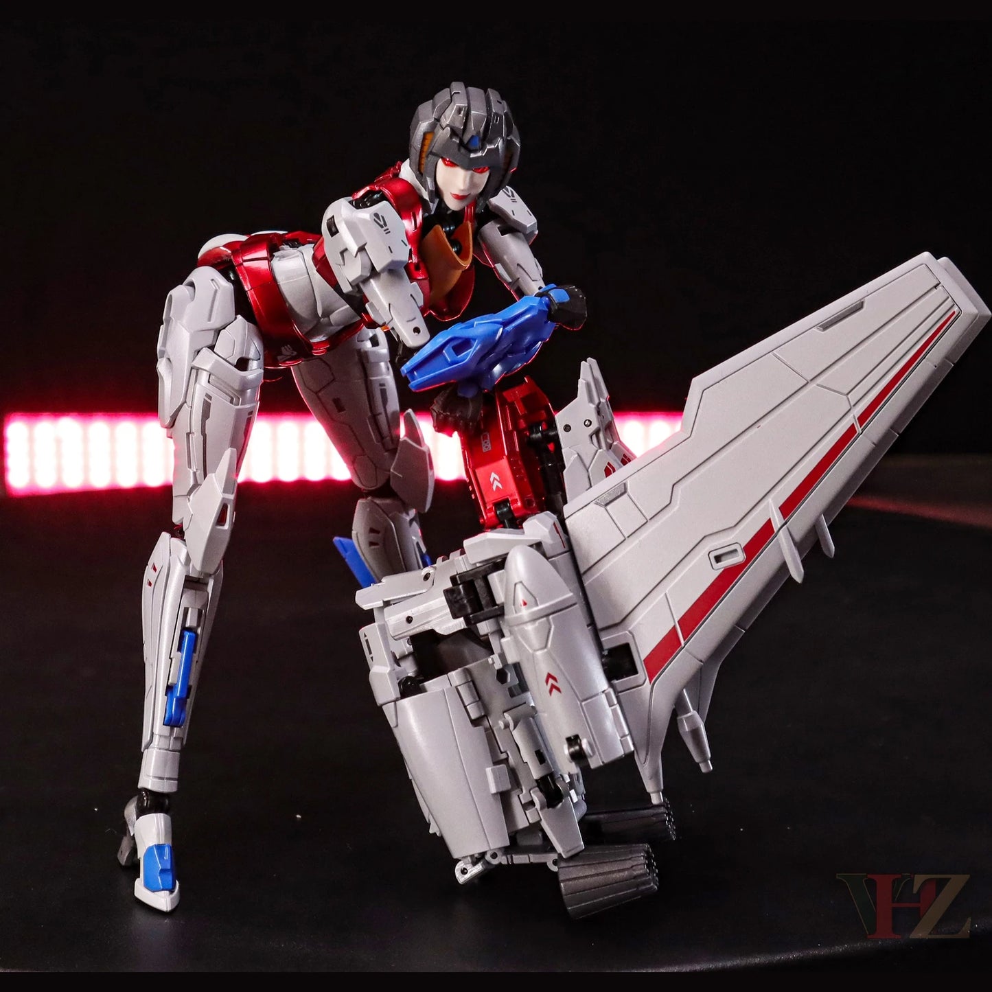 Collection Space CS-03 Starqueen Starscream Mecha Girl in action pose with jet mode, red/silver armor, blue weapon, dynamic lighting against black background.